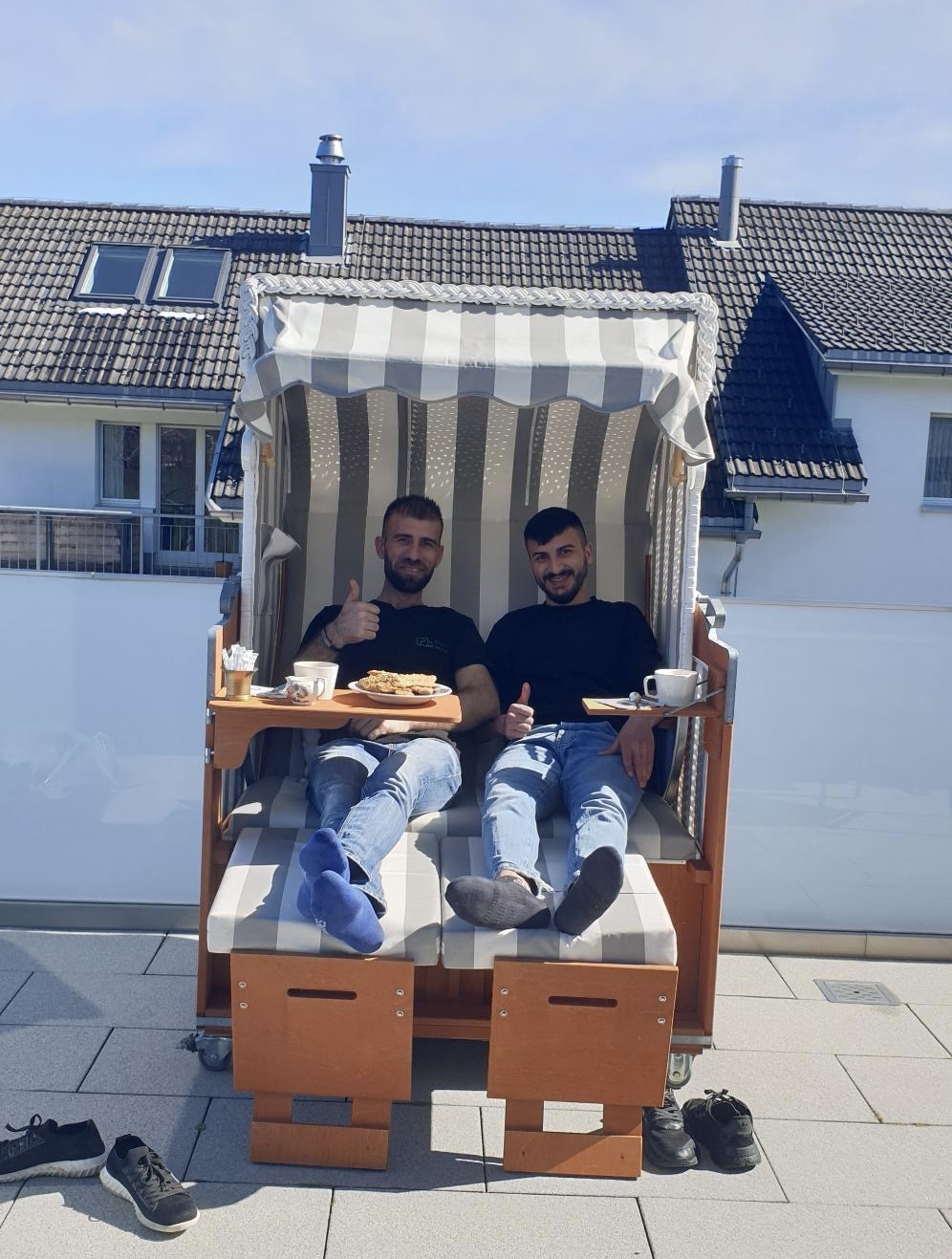 Zwei Mitarbeiter machen Pause in einem gelieferten Strandkorb auf einer Terrasse